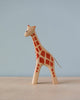 A sustainable Handmade Holzwald Giraffe - Large toy painted with orange spots and a light blue background. The giraffe stands upright and has a detailed face and tail.