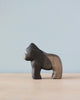 A Handmade Holzwald Gorilla sculpture displayed against a soft blue background, featuring a dark gradient finish from head to tail. This piece represents one of the sustainable toys in our collection.