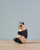 A high-quality Handmade Holzwald Panda, with one half painted black and the other natural, sitting on a grey surface against a pale blue background.