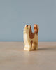 A high-quality Handmade Holzwald Cat figurine with painted details stands on a smooth surface against a soft blue background. The figurine has a thoughtful expression and a curved tail.
