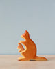 A Handmade Holzwald Kangaroo With Baby sculpture of a cat sitting upright and viewed from the side, placed against a soft blue background. The cat figure is stylized with clean lines and smooth surfaces.