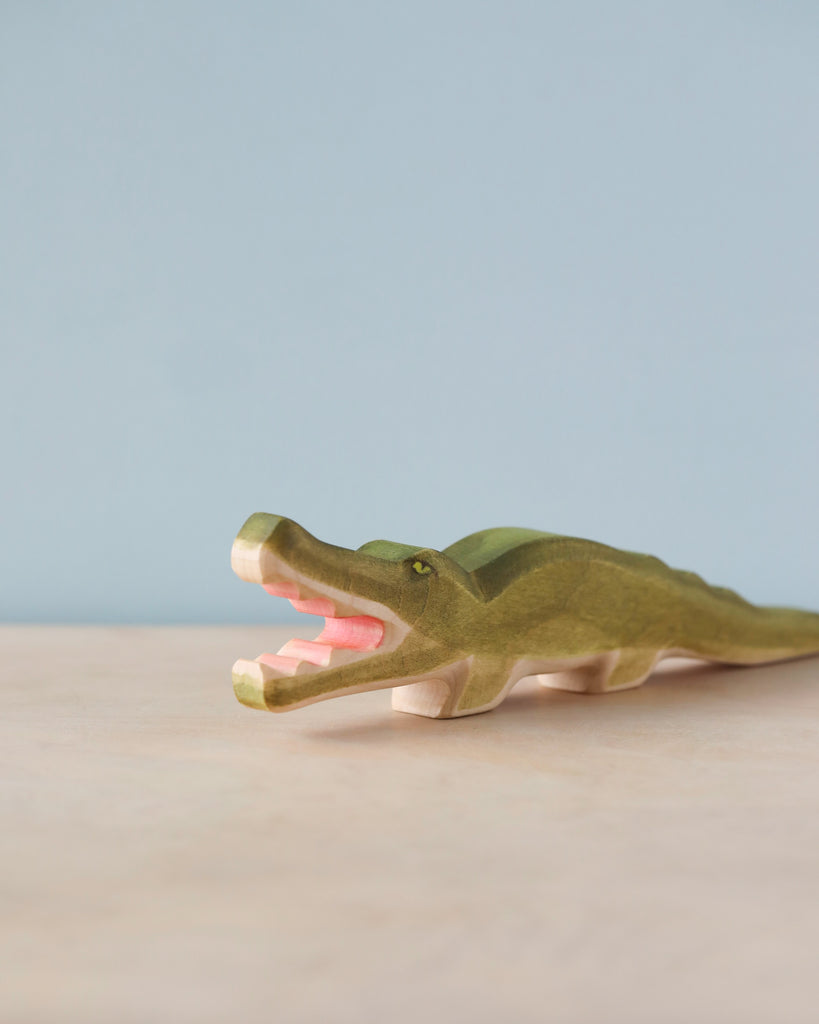 Handmade Holzwald Crocodile from Holzwald Brand on a blue and beige background, featuring visible wood grain and a painted open mouth with pink interior.