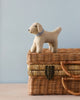 Sentence with product name: A Hand Felted Wool Golden Retriever Dog stands on a wicker box with a light blue background. The puppy is beige with a blue collar, and the box features a metal.