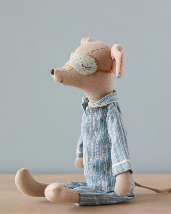 A Maileg Medium Mouse in Pyjamas in a seated position, wearing a blue and white striped shirt and a tan eye patch. The mouse has subtle pink tones in its ears and nose, set against a soft blue.