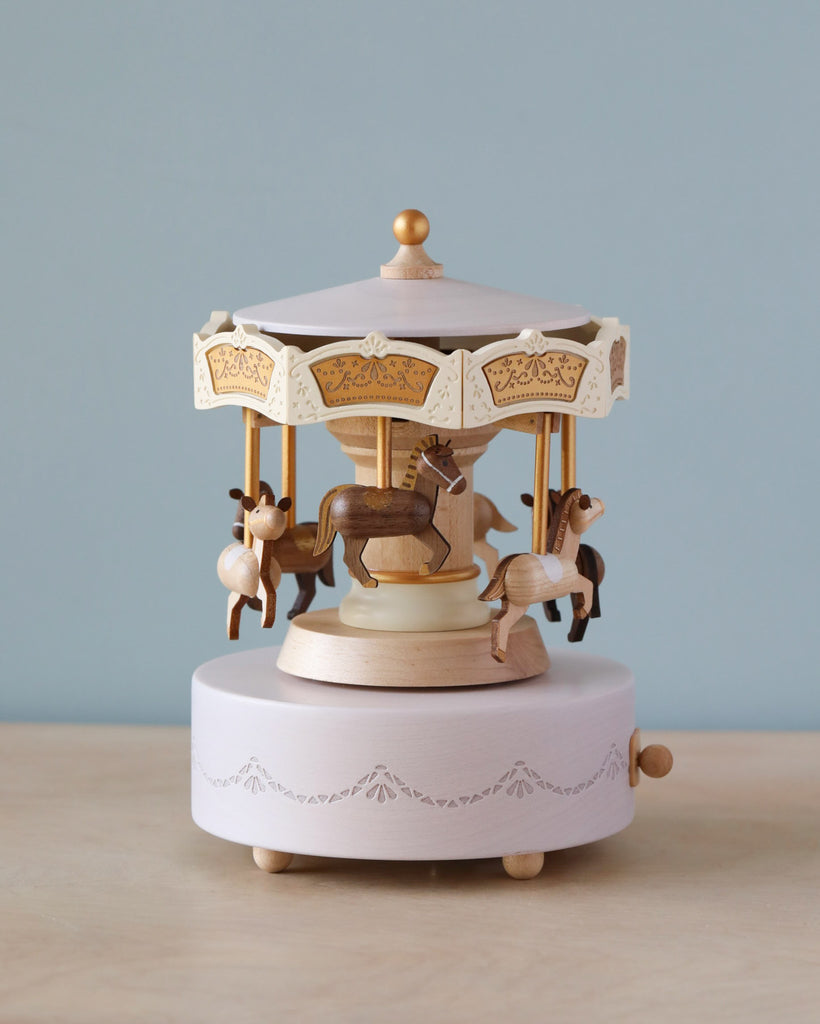 Wooden carousel music box with engravings gold detail. Six horses in dark brown and light brown going around the carouse.  
