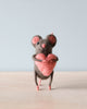A small hand-felted grey mouse holding a pink heart in its arms. 
