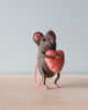 A small hand-felted grey mouse holding a pink heart in its arms.  Photographed showing the profile. 