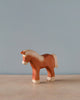 A Handmade Holzwald Light Brown Horse with a smooth finish and high-quality, realistic details, displayed against a plain light blue background.