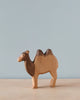 A Handmade Holzwald Camel, a high-quality toy, stands against a plain, light blue background. The camel is crafted with visible wood grains and a smooth finish, displaying two humps and
