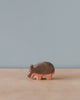 A handmade Holzwald Small Hippo figurine on a plain surface, with a light blue background. The figurine has distinct, segmented body details and pink legs.