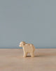A Handmade Holzwald Lamb Standing figurine, displayed on a wooden table against a pale blue background. The lamb is simplistic in design with visible wood grain, epitomizing the charm of sustainable toys.