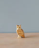 A small, intricately carved Handmade Holzwald Owl figurine stands on a light wood surface against a plain light blue background. This piece is one of our sustainable toys.