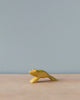 A Handmade Holzwald Jumping Frog, painted yellow, positioned on a flat surface against a plain light grey background, from the Holzwald Brand.