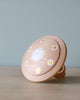 A Handmade Wooden UFO With Alien hand painted with a simple white and yellow sun design on a light blue background.