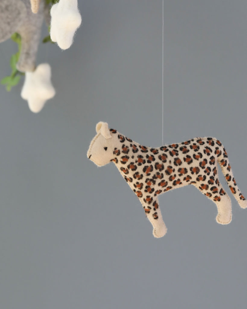 A Handmade Mobile - In The Jungle - Final Sale, adorned with detailed leopard spots, suspended by a thin string against a soft grey background, designed as part of nursery mobiles to encourage visual development.
