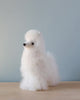 A small Fluffy Alpaca Stuffed Animal resembling a poodle, handmade from luxurious alpaca wool, sits against a pale blue background. The toy has a cute black nose and is shaped in an intricate design.