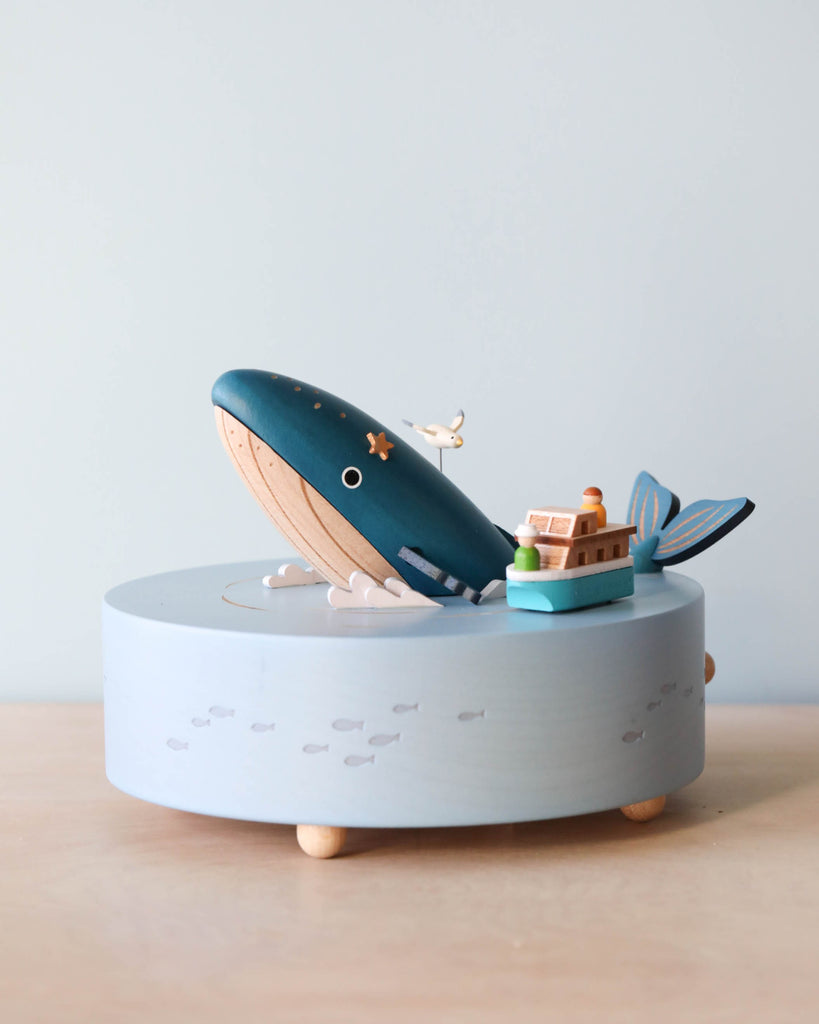 Wooden ocean themed music box with a blue whale in the center and a boat going around it. 
