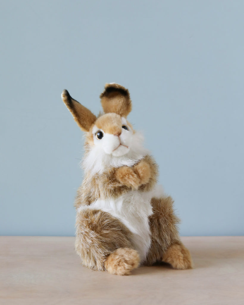 Thumper Rabbit Stuffed Animal crafted with high-quality materials, featuring brown and white fur, sitting on a wooden surface against a light blue background. The rabbit has upright ears and is looking upwards.