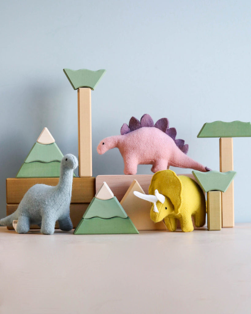 three stuffed dinosaur toys standing on wooden blocks.