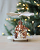 A Christian Ulbricht Snowman Pyramid handmade in Germany, featuring a snowman, trees, and birds with pyramid candleholders, displayed in front of a softly lit Christmas tree.