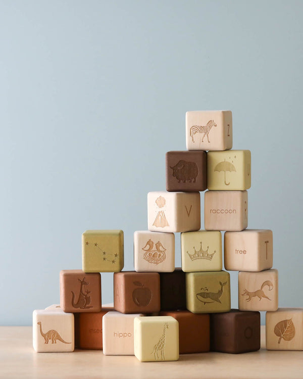 A stack of Alphabet Wooden Blocks - Olive from Sabo Concept, featuring various animal images and words, arranged pyramid-style against a plain light blue background.