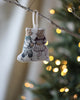 A festive fabric ornament depicting the Coral & Tusk Ice Skater Bears Ornament, hanging on a Christmas tree, with soft glowing lights in the background.