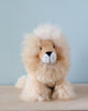 A handmade Fluffy Lion Stuffed Animal with a fluffy mane sitting against a light blue background. The lion has a friendly expression, with black dot eyes and a white snout.