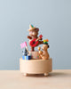 A Mini Wooden Party Music Box from Wooderful Life featuring two bears playing musical instruments; one with a guitar and hat, the other with maracas, standing on a round base against a plain backdrop.