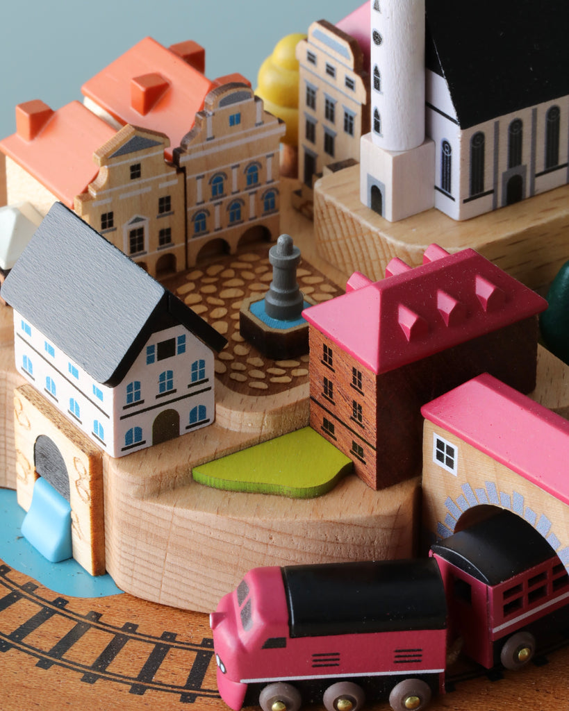 wooden music box with a town in the middle and red train going around it