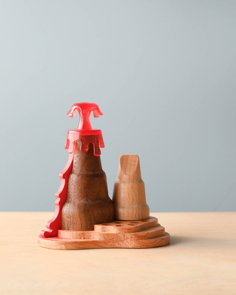 Wooden Dinosaurs representing a king and queen, set against a plain background. The king piece is uniquely shaped with a striking red crown and features pre-historic decorations.
