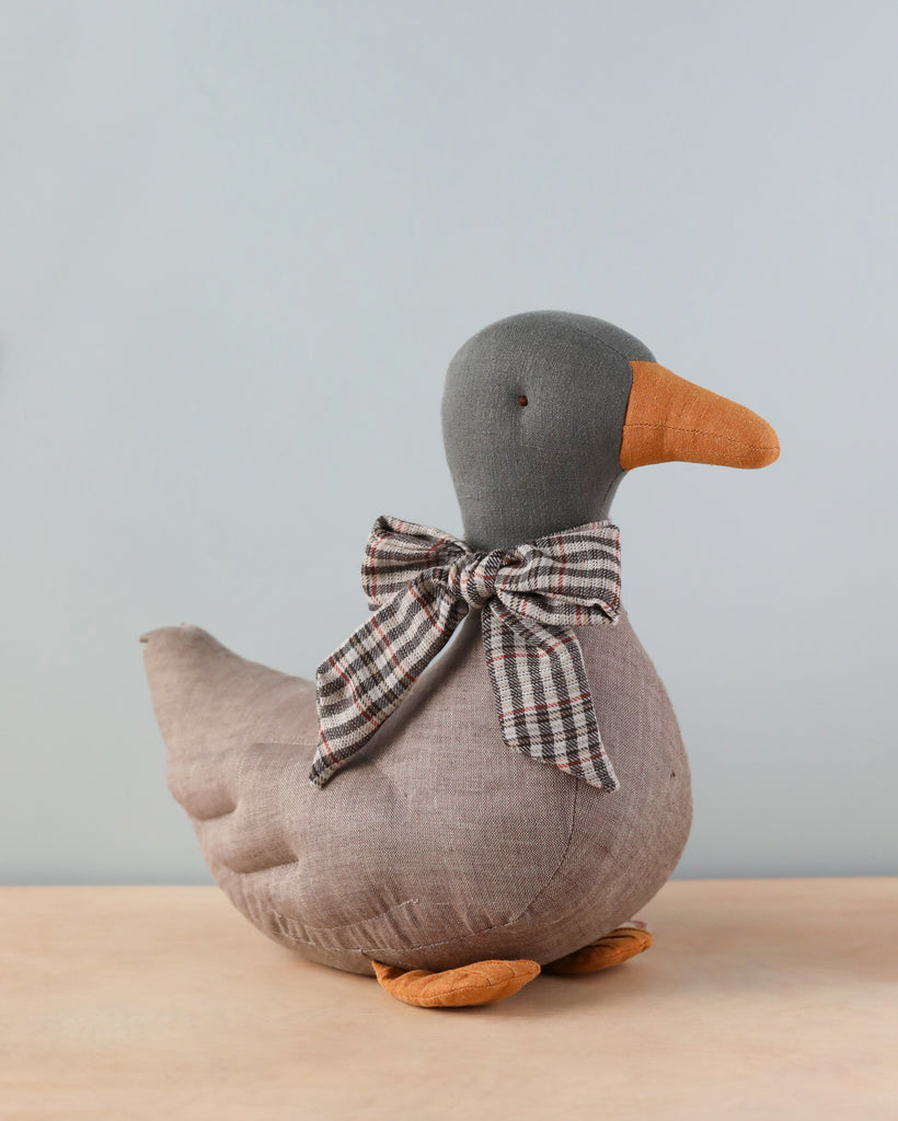 A festive season decor Maileg Duck Stuffed Animal - Gray with a gray head, orange beak, and plaid bow around its neck, standing against a neutral background.