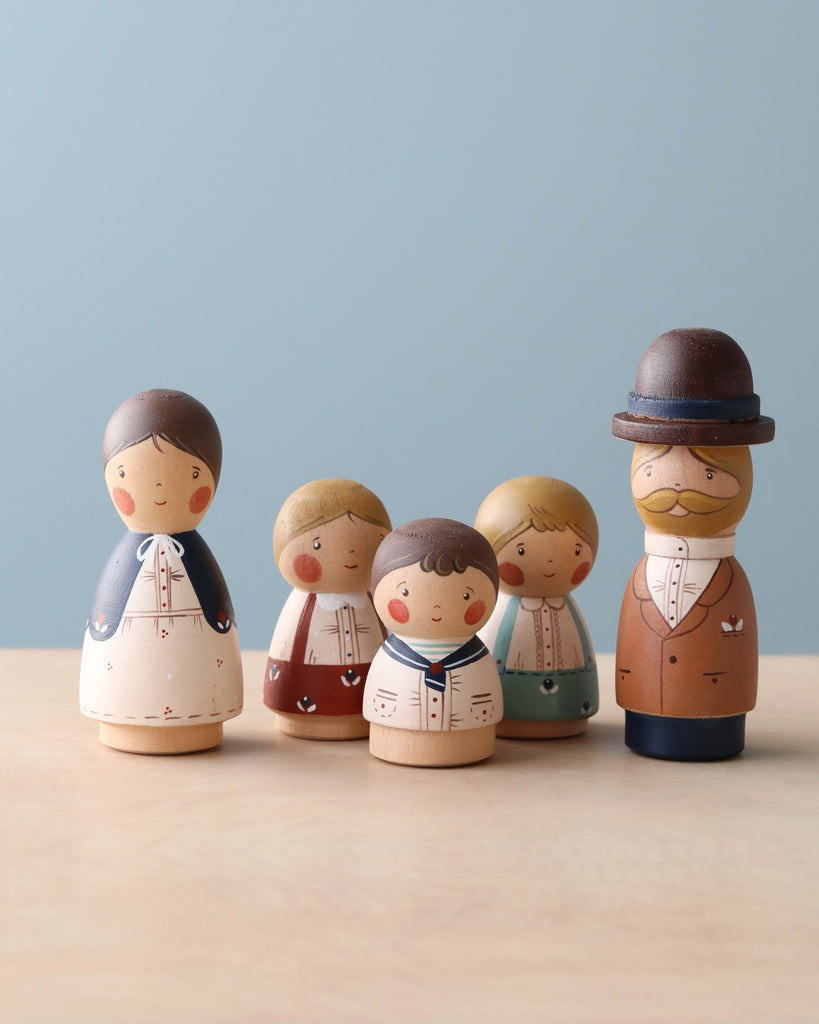 A collection of five Handmade Peg Doll - Girl With Braided Hair depicting a family, arranged in a row against a plain background. The figures vary in size and are hand-painted with different outfits, including a uniform and dresses.