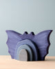 A set of purple wooden bat-shaped nesting shelves, crafted from non-toxic dyed poplar hardwood, on a wooden table against a pale blue background.