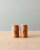 Wooden pretend play salt and pepper shakers standing next to each other. Natural color counter and light blue background. 