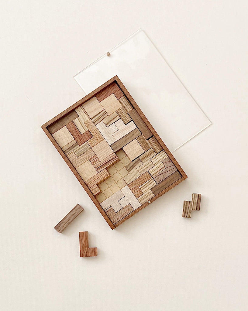 A Wooden Puzzle, partially completed, is displayed on a light background. Several wooden toy pieces are fitted inside a square frame, while a few lie outside.