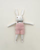 A Polka Dot Club Cream Rabbit in Hand Knit Overalls toy with white and pink features, lying flat against a neutral background.