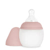 A Medical Grade Silicone Baby Bottle with a transparent, anti-colic teat and a white body, featuring a pink silicone sleeve and matching dome cap, isolated on a white background.