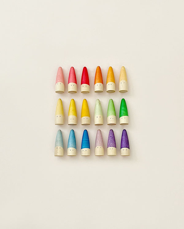 Twenty colorful, wooden, cone-shaped Grapat Sticks Gnomes organized in rows by color gradient from pink to green on a light background.