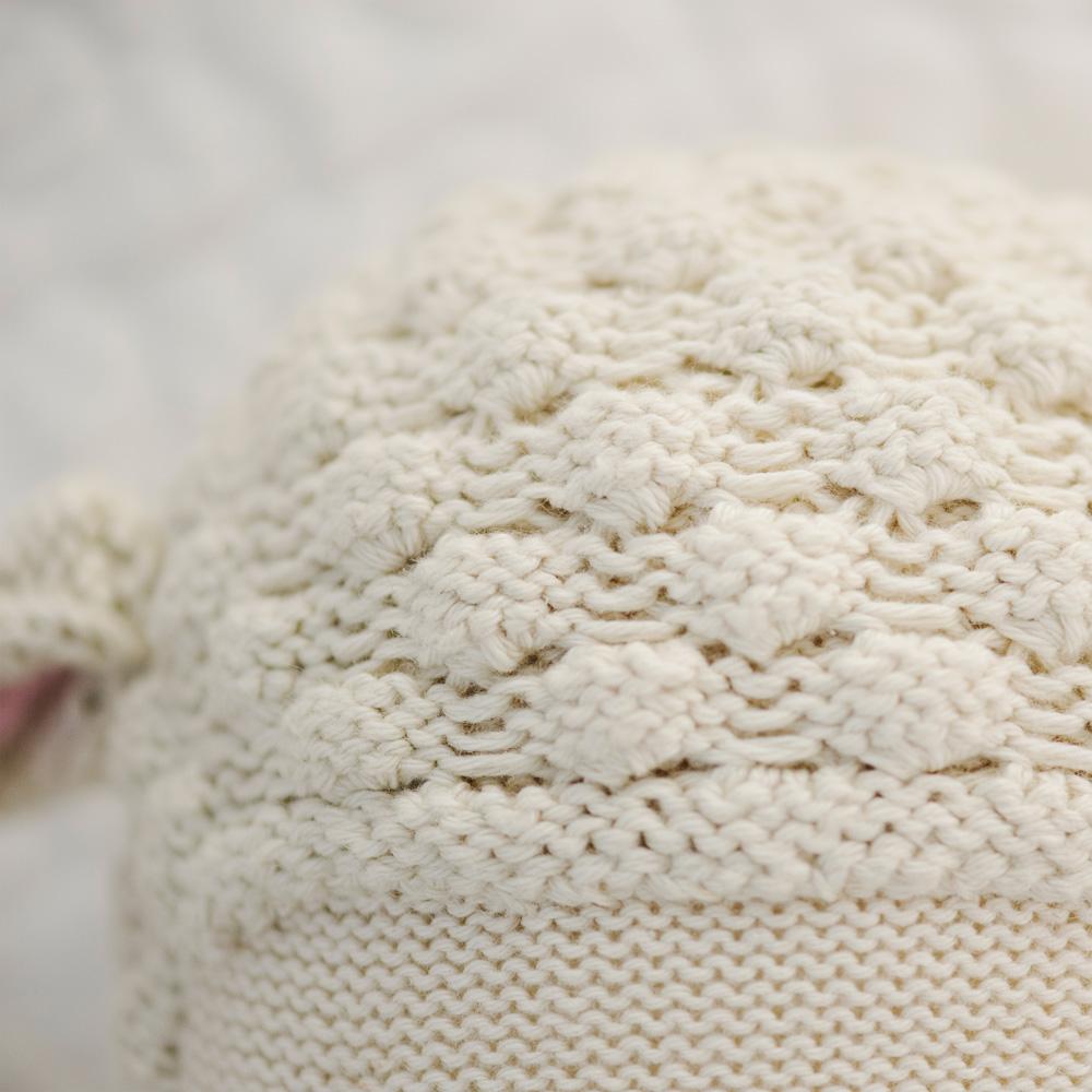 Close-up view of a textured cream-colored Cuddle + Kind Lamb Stuffed Animal, showing detailed stitching patterns.