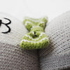 Close-up of a Cuddle + Kind Dog Stuffed Animal showing detailed stitching and textures, focusing on its green and white crocheted bow tie.