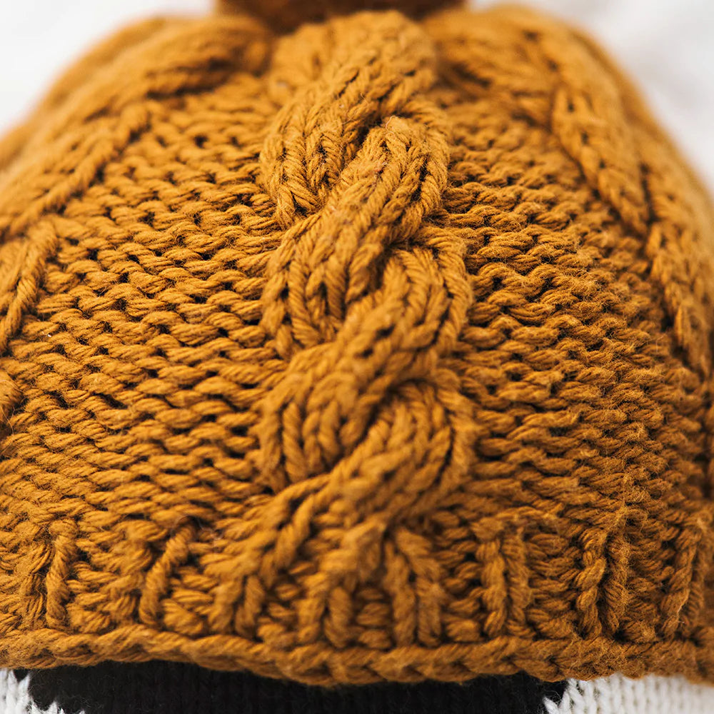 Close-up of a Cuddle + Kind Everest The Penguin hand knit cotton beanie displaying intricate cable knit patterns.