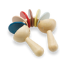 Two sustainably made Clatter Percussion Toys with colorful tops lined up alongside each other against a black and white gradient background.