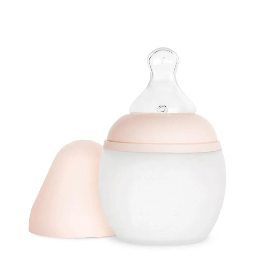 A Medical Grade Silicone Baby Bottle with a translucent body and a peach-colored lid, accompanied by a matching silicone nipple, isolated on a white background.