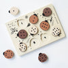 Wooden Tray Puzzle - Count to 10 Ladybugs with various abstract face designs on circular pieces, set against a white background. Each piece fits into corresponding slots on a cream-colored board made from sustainably sourced rubberwood.