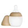 A beige and white Medical Grade Silicone Baby Bottle with a silicone anti-colic teat and removable lid, isolated on a white background.