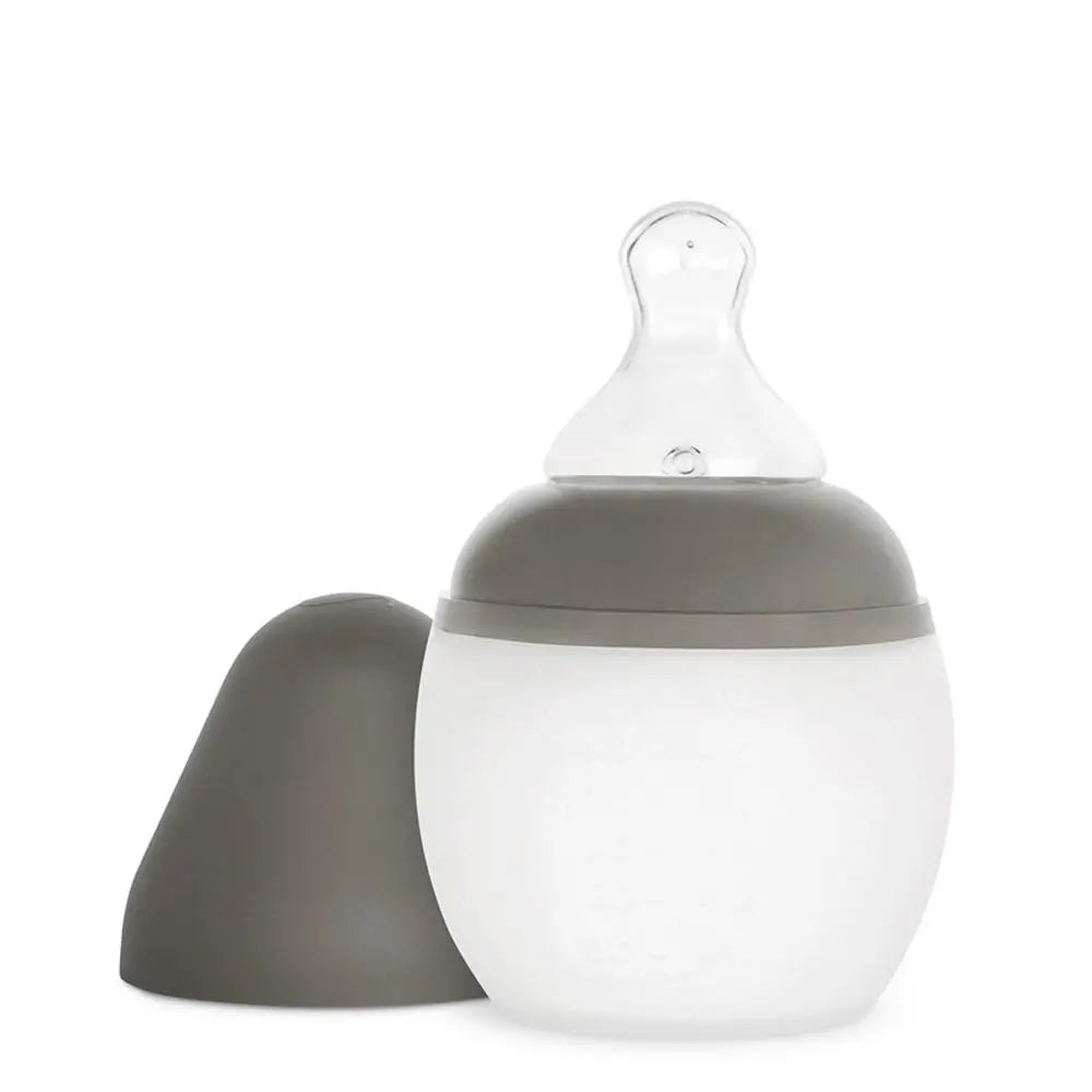 A Medical Grade Silicone Baby Bottle with a translucent body and a gray cap, designed to mimic breastfeeding, isolated on a white background.