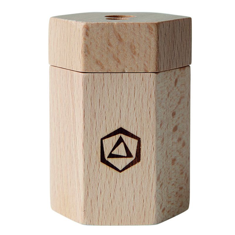 A simple wooden toothpick dispenser made from Stockmar Dual Pencil Sharpener certified lime wood, with a hexagonal shape and a small pentagon logo burned into one side, viewed against a white background.