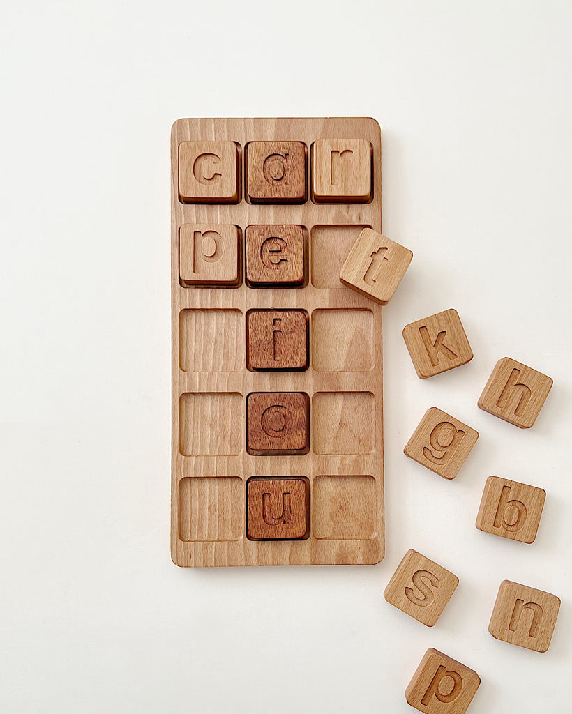 Extra Large CVC Word Kit - Made in USA partially arranged in a tray on a white background. Some letters are placed in the slots while others are scattered beside the tray. These wooden educational toys are great for learning letters.