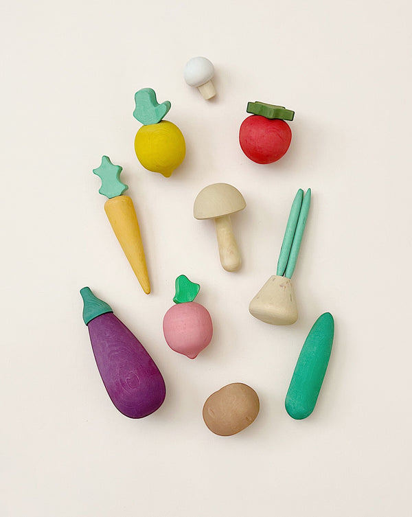 The Raduga Grez Handmade Wooden Vegetable Set, featuring a vibrant array of handcrafted wooden vegetable toys such as a carrot, tomato, eggplant, radish, cucumber, potato, and mushroom, is beautifully displayed on a light background.