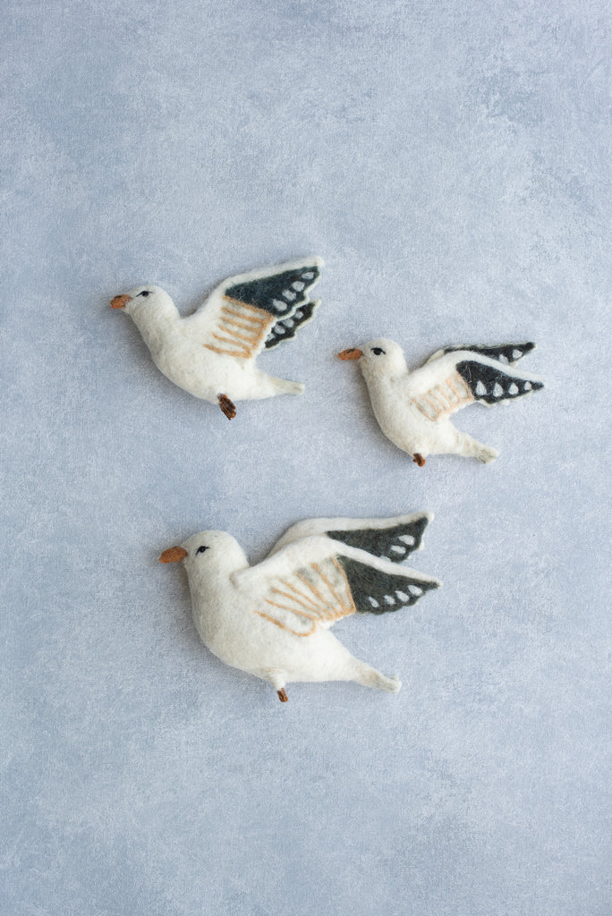 Three Flying Seagulls Wall Decor with white bodies and detailed wing patterns arranged on a light blue textured background.